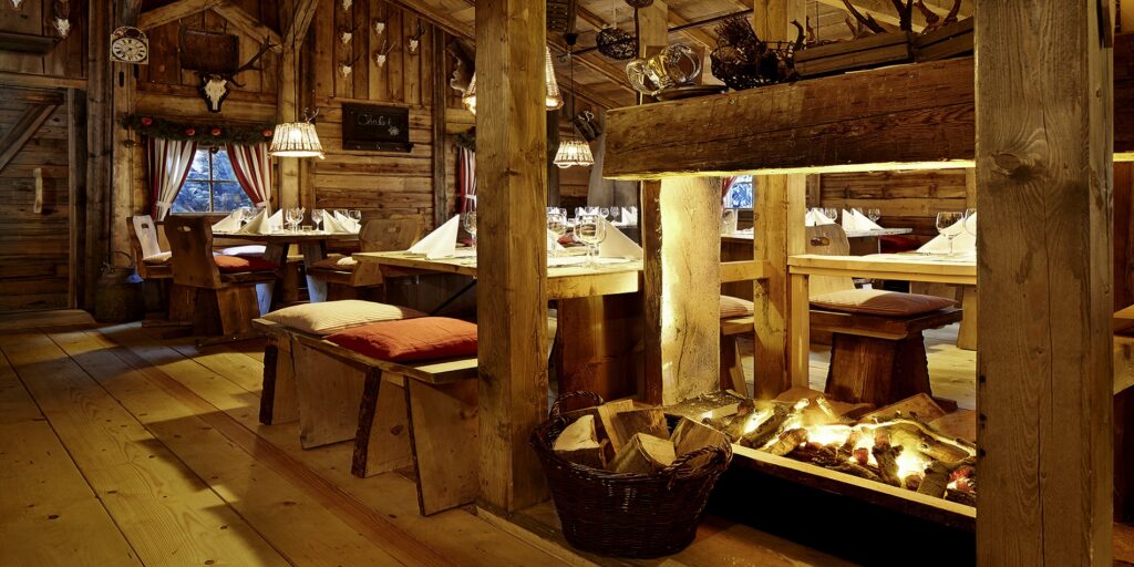 Rustikales Alpen-Chalet mit gemütlichem Kamin, Holztischen, gedeckten Plätzen und warmem Hütten-Ambiente