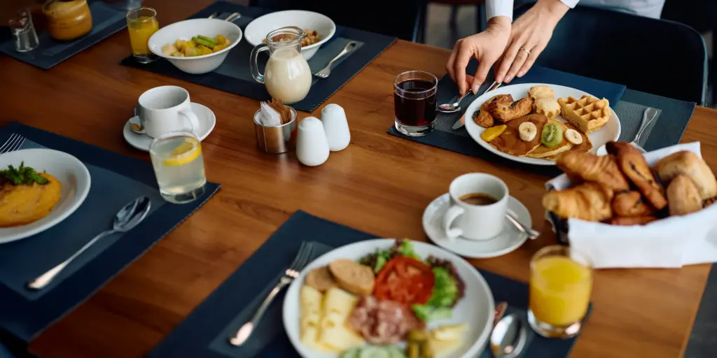 Frühstückstisch mit Pfannkuchen, Croissants, Obst, Saft und Kaffee – reichhaltige Auswahl für einen genussvollen Start.
