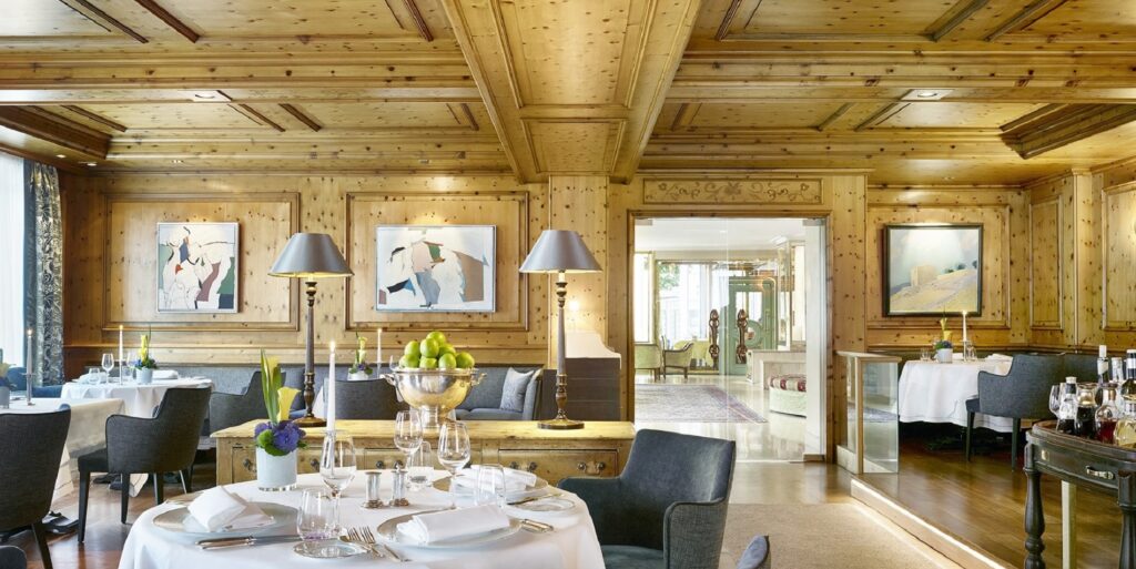 Elegantes Restaurant mit Holzvertäfelung, gedeckten Tischen, Kerzenlicht, moderner Kunst und gemütlicher Atmosphäre