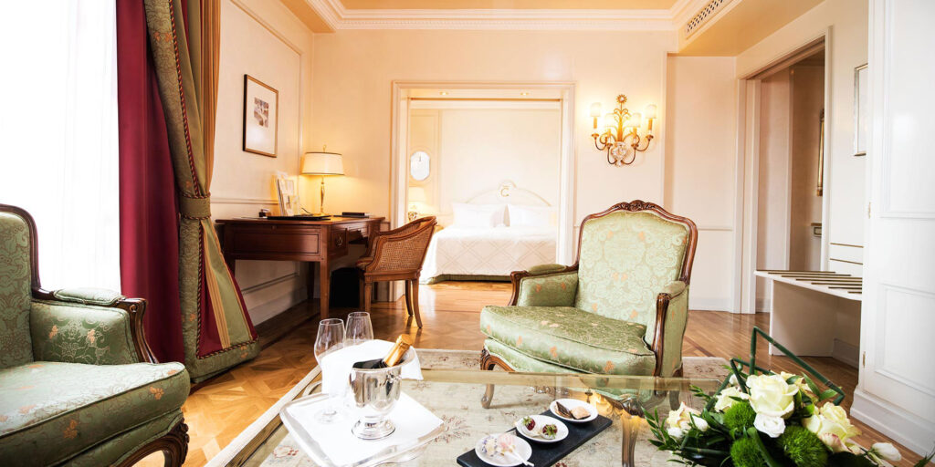 Luxus-Hotel-Suite mit elegantem Wohnbereich, antiken Möbeln, Schreibtisch, Champagner und en-suite Schlafzimmer